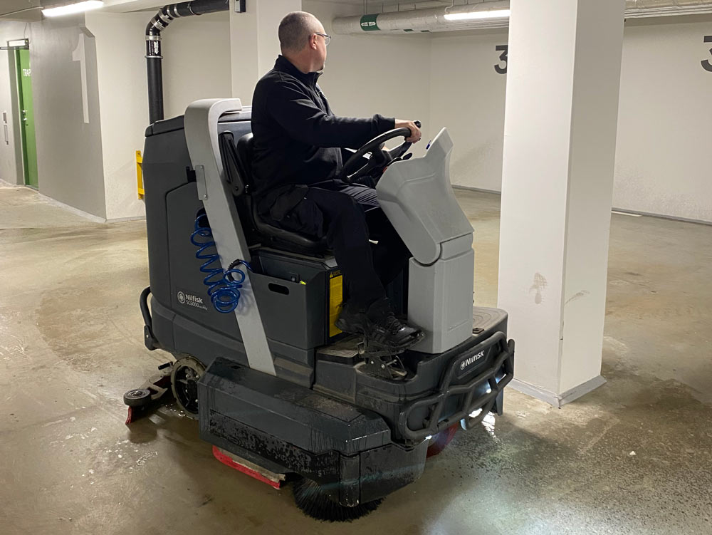 En man kör en maskin för städning i ett garage