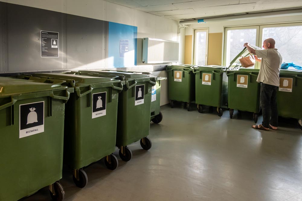 En man slänger sina sopor i ett miljörum